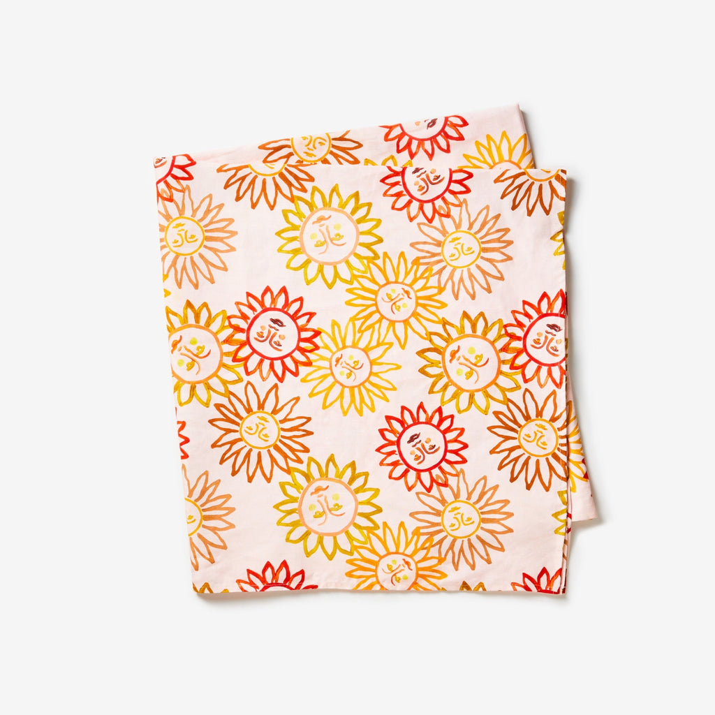 Hand painted sun motifs in varying shades of bright yellow, orange and bright red. Set on a dusty pink background.